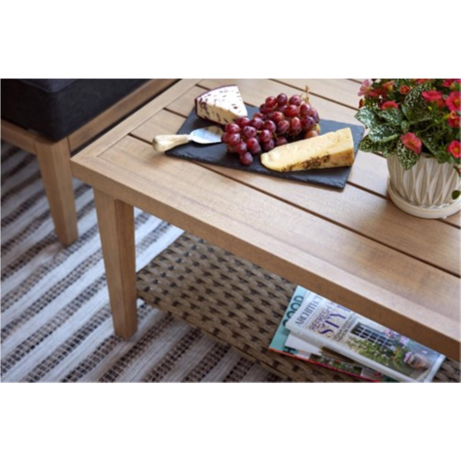 Cheese and grapes on a wooden patio table with a magazine underneath
